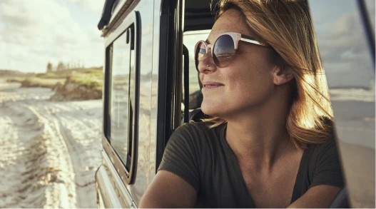 a woman looking out of a car window at the beach